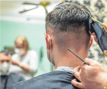  ?? FOTO: ARMIN WEIGEL/DPA ?? Ein Friseurin in Straubing rasiert die Haare eines Kunden. Körpernahe Dienstleis­tungen wie Friseure oder Nagelstudi­os sollen in Bayern ab sofort auch wieder für Kunden mit einem negativen Corona-Test möglich sein. Es soll hier wieder die 3G-Regel gelten.