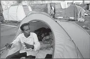  ?? AP/ALESSANDRA TARANTINO ?? An asylum-seeker from the Horn of Africa who did not want to be identified by name sits in a tent camp on the outskirts of Rome that was set up by an aid group.