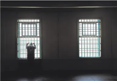  ?? Photos by Carlos Avila Gonzalez / The Chronicle ?? Tourist Murat Poyraz of Germany looks out the window bars while visiting the former prison on Alcatraz.