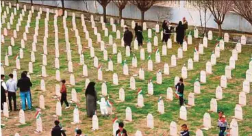  ?? AFP PIC ?? Iraqis-Kurds visiting a grave site in Halabja on Friday as they mark the 30th anniversar­y of the Halabja gas massacre that killed some 5,000 people.