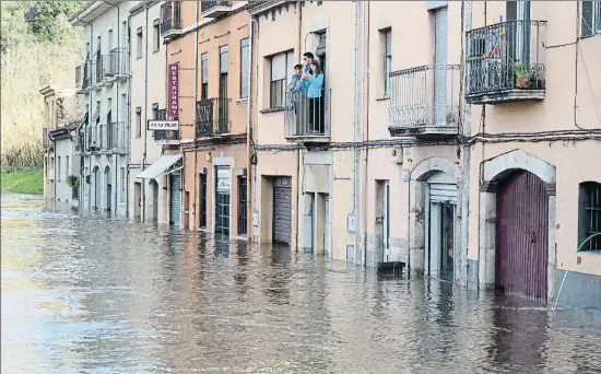  ?? PERE DURAN / NORD MEDIA ?? Confinados. Unos vecinos del anegado barrio del Pont Major, en Girona, observan desde el balcón su calle convertida en un río