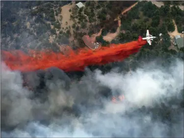  ?? JOHN WARK — THE ASSOCIATED PRESS FILE ?? An aircraft lays down a line of fire retardant between a wildfire and homes in the dry, densely wooded Black Forest area northeast of Colorado Springs on June 13, 2013. A federal judge said Friday that chemical retardant dropped on wildfires by the U.S. Forest Service is polluting streams in western states in violation of federal law, but said it can keep being use to fight fires.