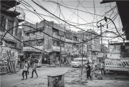  ?? Sergey Ponomarev/new York Times ?? Residents of Baghdad walk under electrical wires in 2021. Twenty years after the invasion, Iraq, the Middle East and the world are better off for having gotten rid of Saddam Hussein.