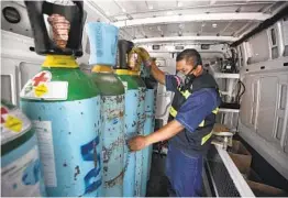  ?? MARCO UGARTE AP ?? Jose Antonio Peña refills oxygen tanks for COVID-19 patients in the Iztapalapa district of Mexico City. The city is offering free oxygen refills for patients.