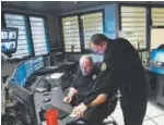  ??  ?? Delta County sheriff ’s Deputies Tim Hatch, left, and Tom Barker talk as Hatch monitors 96 security cameras at the department.