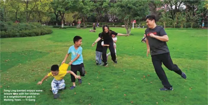  ?? ?? Tong Ling (center) enjoys some leisure time with her children in a neighborho­od park in Meilong Town. — Ti Gong