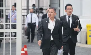  ?? APICHART JINAKUL ?? Watana Muangsook, left, leaves the Supreme Court after posting a 10-million-baht bail.