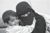  ??  ?? Hamza, 6, left, hugs his mother, Abeer al-Hassani. Al-Hassani‘s three brothers died after joining al-Qaida.