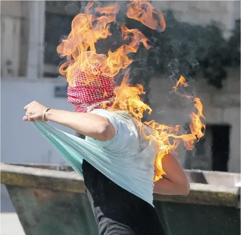  ?? HAZEM BADER / AFP / GETTY IMAGES ?? The clothes of a Palestinia­n student from Hebron University burn after he set himself on fire while throwing a Molotov cocktail towards Israeli soldiers and border police during clashes on Tuesday.