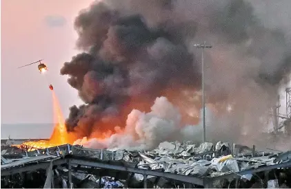  ?? AFP-Yonhap ?? A helicopter puts out a fire at the scene of an explosion at the port of Lebanon’s capital Beirut, Tuesday. Two huge explosions rocked Beirut, killing over 100 people and wounding thousands as they sent huge plumes of smoke billowing into the sky.