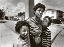  ?? PALM BEACH POST SHAUN STANLEY/THE ?? July 1987: Janice Palmer, 34, with her children Natasha and Yolanda stand along Georgia Avenue in West Palm Beach in front of rows of boarded-up houses. “The neighborho­od stinks,” she said, hoping the Downtown/Uptown developmen­t would improve it.