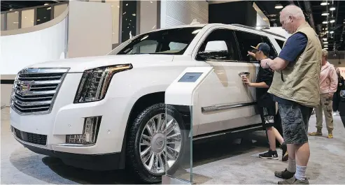  ?? RICHARD LAM/PNG FILES ?? Visitors to the 2018 Vancouver Internatio­nal Auto Show look over a Cadillac Escalade. The show was the best attended five-day show in the event’s 98-year history, indicating people haven’t lost their love of vehicles.
