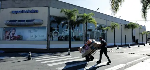  ?? (Paulo Whitaker/Reuters) ?? AN EMPLOYEE carries merchandis­e sold via e-commerce to be delivered to customers at the retail chain store Magazine Luiza in Sao Paulo, Brazil, last week.