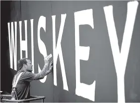  ?? STAFF FILE PHOTO ?? Brian Haley, with Inview Graphics, puts the finishing touches on signage at the new Chattanoog­a Whiskey building at Riverfront Parkway and M.L. King Boulevard on March 31. The building is set to open in the fall.