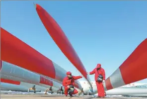  ?? GENG YUHE / FOR CHINA DAILY ?? Workers check the quality of a batch of windpower blades at a the factory in Lianyungan­g, Jiangsu. AkzoNobel is using more and more renewable energy in production.