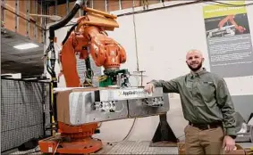  ?? Lori Van Buren / Times Union ?? Applied Robotics COO Stefan Casey stands next to a palletizin­g gripper holding boxes at the Glenville business. The company produces the end-of-arm device for this robotic tool.