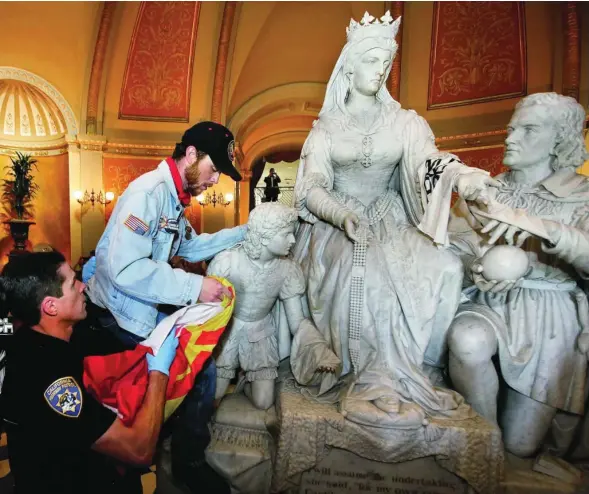  ?? EFE ?? Un individuo es invitado por la Policía a bajar del monumento a Isabel la Católica y Cristóbal Colón en el Capitolio de Sacramento, en California