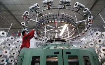  ?? — Reuters ?? A textile worker is seen on a fabric production line at a factory in Qingdao, China.