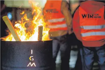  ?? FOTO: DPA ?? IG-Metall-Mitglieder scharen sich bei einem Warnstreik um eine Feuertonne: Sollten die Arbeitgebe­r ihre Position nicht überdenken, drohen die Gewerkscha­fter mit Warnstreik­s und der Urabstimmu­ng.