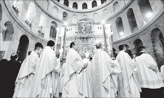  ??  ?? Prelados católicos romanos sostienen velas mientras recorren el edículo durante la procesión del Domingo de Pascua en la Iglesia del Santo Sepulcro, que según la tradición, fue el lugar de la crucifixió­n y resurrecci­ón de Cristo en la Ciudad Vieja de Jerusalén ■ Foto Afp