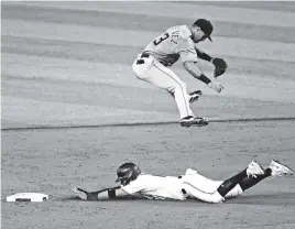  ?? CHARLES TRAINOR JR ctrainor@miamiheral­d.com ?? Miguel Rojas slides safely into second base as infielder Sean Rodriguez leaps after an overthrown ball in a simulated game Monday at Marlins Park.