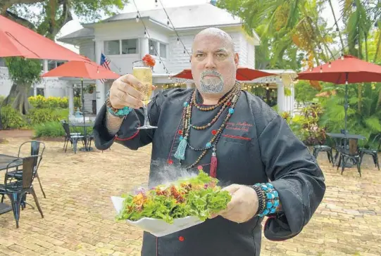  ?? MICHAEL LAUGHLIN/SUN SENTINEL PHOTOS ?? Chef Jonny NoBones displays his smoking salad with oysters on the half shell, champagne and caviar on Aug. 20 outside his Jonny NoBones at The Old Riverhouse Vegan Village.