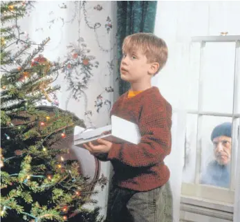  ?? FOTO: DPA ?? Ganz alleine schmückt Kevin (Macaulay Culkin, li.) den Weihnachts­baum, während Schurke Harry (Joe Pesci) draußen auf eine Gelegenhei­t lauert.