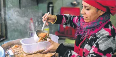  ??  ?? A woman serves food at a soup kitchen at the Villa 21-24 shantytown in Buenos Aires.