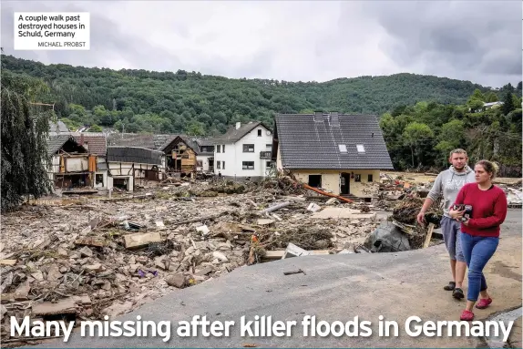  ?? MICHAEL PROBST ?? A couple walk past destroyed houses in Schuld, Germany