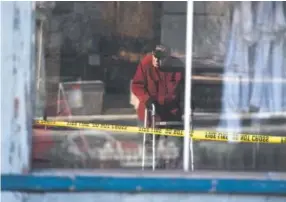  ??  ?? Green Door Furniture owner Al Stewart, reflected in a window of his store, looks at the fire-gutted building Tuesday. Andy Cross, The Denver Post