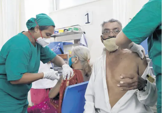  ?? RAJANISH KAKADE/AP ?? Health workers administer the Covaxin vaccine for COVID-19 to elderly people at a vaccinatio­n centre in Mumbai, India, on Thursday. India’s vaccinatio­n drive is faltering just at the time when it is needed the most.