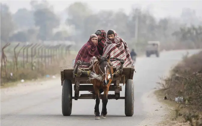  ??  ?? JAMMU: Indians, wrapped in blankets, ride a horse-cart on a cold morning in Jammu, India yesterday. —AP