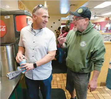  ?? ?? Crye, left, talks with Jason Miller, a Crye supporter and owner of Lucky Miller’s Deli, on Feb. 21 in Miller’s restaurant in Redding.