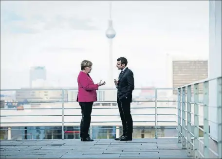  ?? HANDOUT / REUTERS ?? Angela Merkel y Emmanuel Macron hablando distendida­mente el pasado día 15 en Berlín