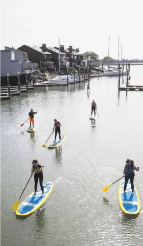  ?? PHOTOS BY LAURA MORTON ?? Left: Members of an introducti­on to stand up paddle boarding class paddle from the marina out to the bay during their class at Mike's Paddle in Alameda. Right: Joe Callander reads a book while eating breakfast at Little House Cafe. The restaurant...