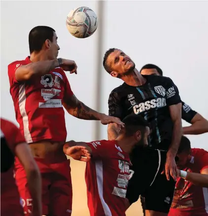  ??  ?? Tarxien's Vito Plut (C) heads the ball despite the close attention of Juan Bolano (L) of Gudja United. Photo:Domenic Aquilina