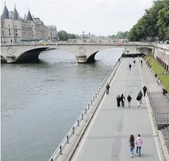  ??  ?? People stroll along on the banks along the Seine River Monday in Paris. The French began leaving their homes and apartments for the first time in two months without permission slips as the country cautiously lifted its lockdown.