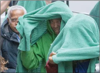  ??  ?? Hidden: Migrants put blankets over their heads as they arrive in London