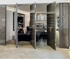  ??  ?? Warm taupe vintage chairs and stools from architect and designer India Mahdavi can be found in this walk-in wardrobe (top); sleek rotating doors of the TV room offer privacy and make a great visual impact (above)