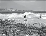  ?? AP/AARON FAVILA ?? A girl walks along the shore in the Philippine­s province of Quezon as strong waves from Typhoon Hagupit roll in Saturday.