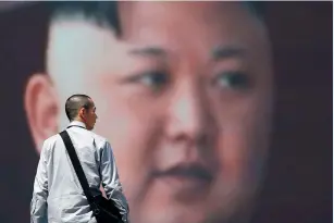  ?? (Toru Hanai/Reuters) ?? A MAN walks past a street monitor showing a picture of Kim Jong-un in Tokyo on Saturday.