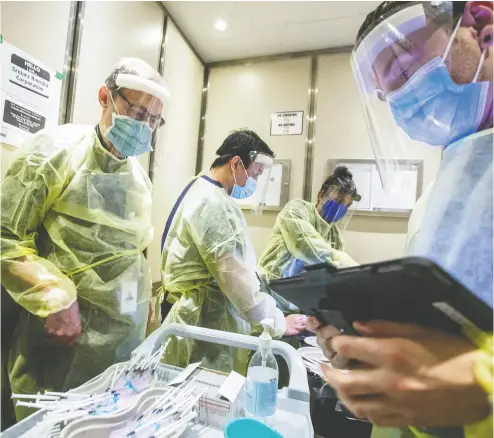  ?? CARLOS OSORIO / FILES ?? Nurses and doctors ride an elevator as they prepare to administer a COVID-19 vaccine at a seniors building
in Toronto. As the virus threat recedes, doctors should return to normal practice, says Randall Denley.