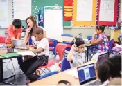  ?? MATT ROTH FOR THE NEW YORK TIMES ?? A teacher helped second graders at Church Lane as they worked on their HP devices, which can convert from laptops into tablets. The district has committed more than $200 million for the laptops