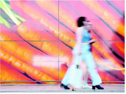  ?? AP ?? Shoppers walk past a large poster outside a supermarke­t in London on June 10, 2023. Inflation in the United Kingdom held steady at four per cent in January as lower food prices helped offset an increase in energy costs, official figures showed on Wednesday.