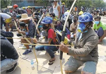  ?? AP ?? Protesters prepare makeshift bows and arrows to confront police in Thaketa township, Yangon, Myanmar, on Saturday. More than 100 protesters were reportedly killed Saturday throughout Myanmar.