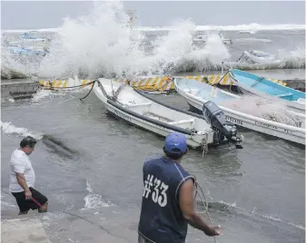  ?? THE ASSOCIATED PRESS ?? Fishermen remove their boats from the dock in the Veracruz state of Mexico as Hurricane Grace swept along the Gulf coast before heading inland on Saturday.