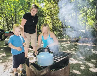  ??  ?? Two-year-old Ben Olive, his mother Ashley Olive, right, and his grandmothe­r Debra Page start one last fire before restrictio­ns at Goldstream Park and other parks in the coastal region take hold at noon today.