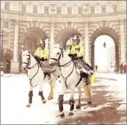  ??  ?? Mounted police officers ride through the snow in front of Admiralty Arch in London