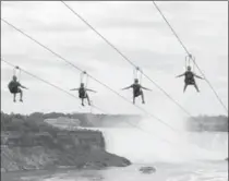  ?? KIEN TRAN, THE ASSOCIATED PRESS ?? Tourists suspended above the water from zip lines make their way at speeds of up to 64 km/h toward the mist of the Horseshoe Falls.