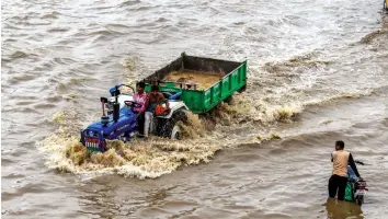  ?? — PTI ?? A tractor wades through a waterlogge­d road after heavy rains in Gurgaon on Tuesday.